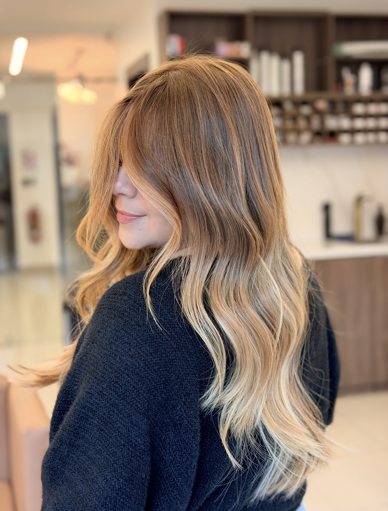 Rubio balayage cálido con caída ondulada, resultado insignia del estudio